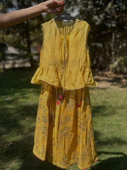 This yellow lehenga set features a peplum top with ruffles and a printed skirt with delicate tassels. This image shows the fine details that make my outfits unique and special.