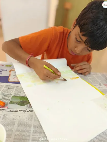 A young boy carefully adds a watercolor background to his piece before starting the lettering, learning about composition and color.