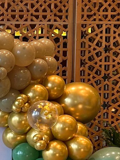 A close-up of a sophisticated balloon garland in sage green, beige, and gold chrome. This color palette is perfect for a modern and stylish jungle or safari theme.