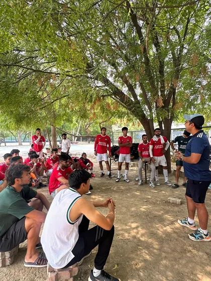 A team talk under the shade of a tree, showing how we adapt and strategize in any environment. This is grassroots football with a professional mindset.