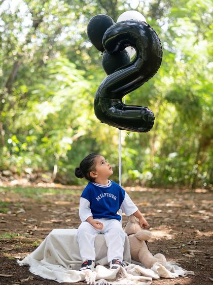 A quiet moment for the "Biker Boy" looking up at his number '2' balloon. This shot captures the wonder and curiosity of a two-year-old.