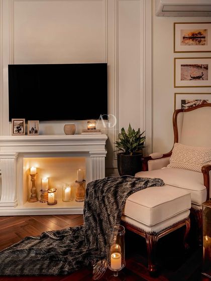 The same reading corner at night, with the faux fireplace lit by candles. This creates a warm and romantic atmosphere, showcasing how lighting can transform a space.