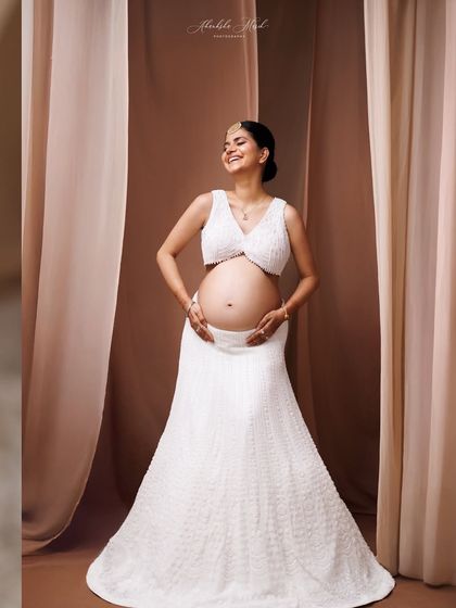 Modern elegance in a white two-piece lehenga-style outfit. This look is perfect for showcasing the baby bump with a blend of traditional inspiration and contemporary fashion.