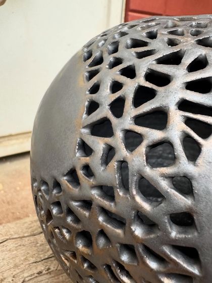 This wheel-thrown stoneware sphere features an intricate, hand-carved geometric pattern. I added a touch of gold to the metallic glaze to highlight the cuts and create a sense of depth.