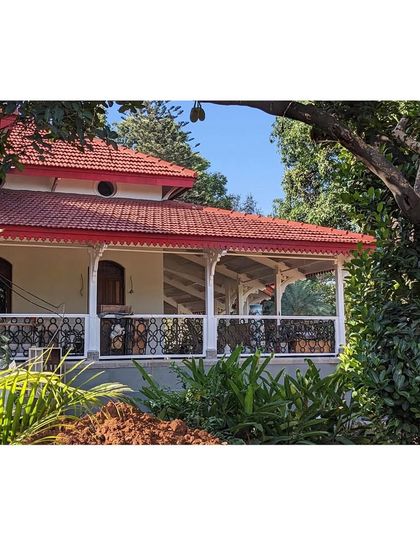 The restored veranda with its striking red-tiled roof and intricate white metalwork. This space is a perfect example of the building's blend of colonial and vernacular architectural styles.
