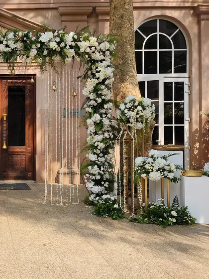 Another angle of the elegant white floral arch, perfectly framing the venue's classic wooden doors.