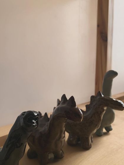 A herd of tiny dinosaurs, fresh from the kiln. These miniature sculptures are glazed in earthy, muted tones and are perfect for adding a touch of prehistoric fun to a shelf or desk.