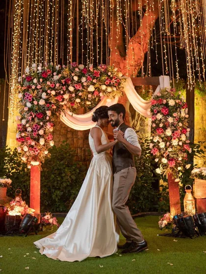 The first dance under a canopy of fairy lights. For this Christian wedding reception, we created a romantic floral arch and used warm lighting to set a magical mood.