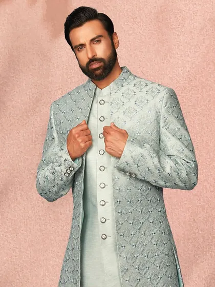 This powder blue layered sherwani has a subtle, regal feel. The intricate self-pattern on the jacket adds a layer of sophistication.
