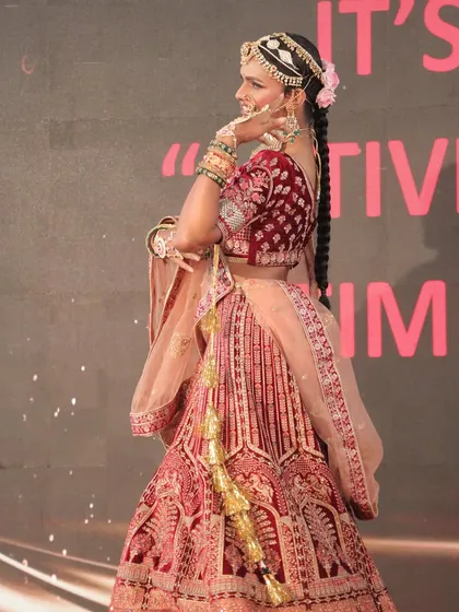 The transformed model seen from the back, showcasing the intricate hairstyle with a long braid and the stunning embroidery of the velvet lehenga.