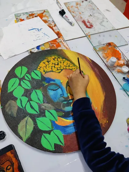 Multiple students are seen working on their own interpretations of Buddha paintings, showcasing a calm and focused studio environment.