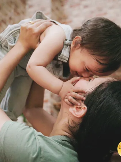 A mother lifts her child in a sweet embrace, capturing a moment of pure love and joy.