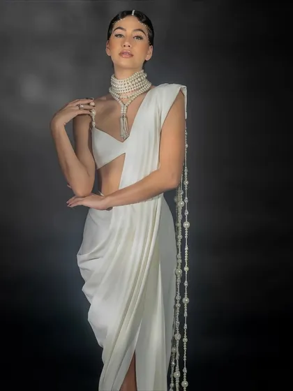 An elegant, posed shot for Nikhil Thampi, highlighting the graceful lines of the saree and the cascading pearl details.
