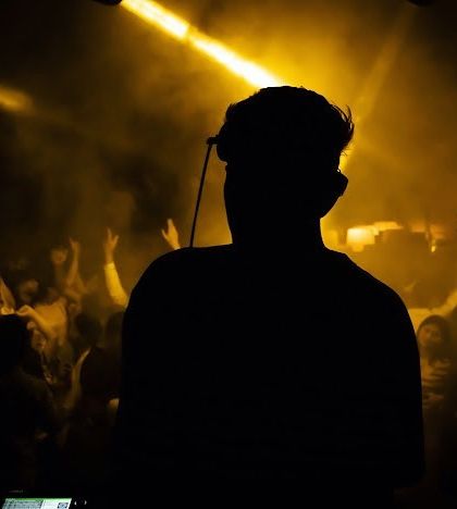 A silhouette shot of me against a packed, hazy club. This artistic photo captures the mysterious and powerful presence of a DJ in control of the night.