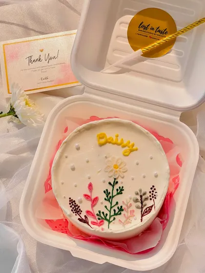 A delicate "Daisy" bento cake with hand-piped wildflowers and leaves. This design has a charming, botanical feel perfect for a nature lover.