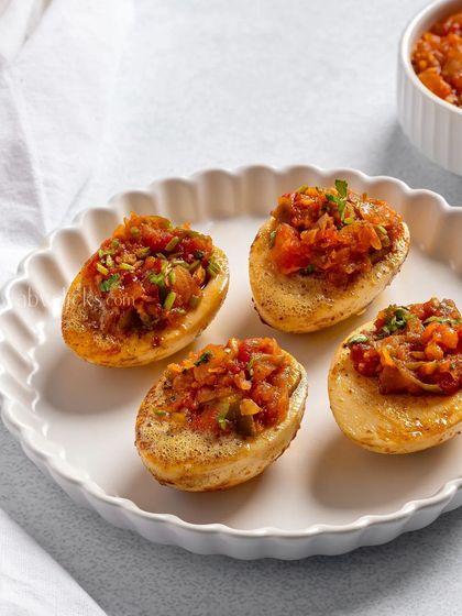 Small potato skins stuffed with a savory tomato filling, a perfect bite-sized appetizer.
