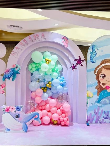 We created an enchanting 'Under The Sea' world for Samara's birthday. The stage features pastel-colored backdrops, cute sea creature cutouts like an octopus and whale, and a large light-up number '6'.