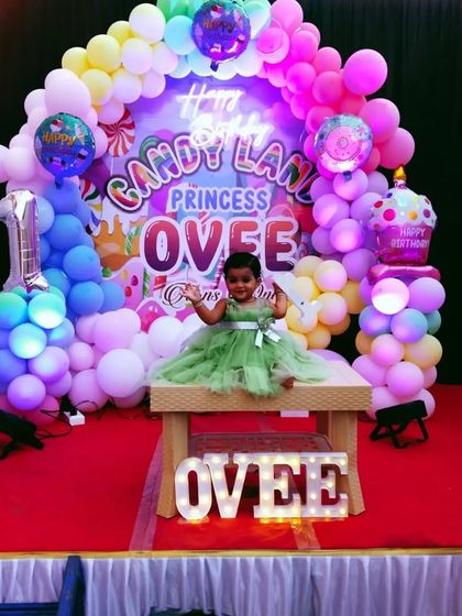 A clear shot of the Candy Land stage, showing the neon sign, custom backdrop, and balloon columns with ice cream and cupcake toppers.