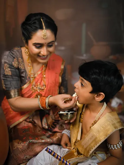 A mother lovingly feeds her son a piece of butter, recreating the classic stories of Krishna and Yashoda.
