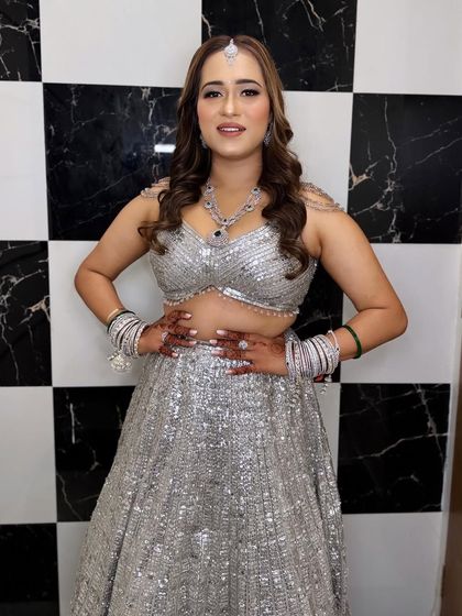 A happy and confident bride ready for her reception. Her silver sequin lehenga sparkles, and the makeup is kept glamorous with a focus on her eyes.