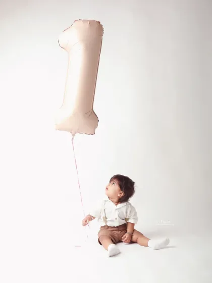 A simple, yet profound portrait of a baby boy holding a single balloon, looking up as if towards his future. A beautiful way to mark one year.