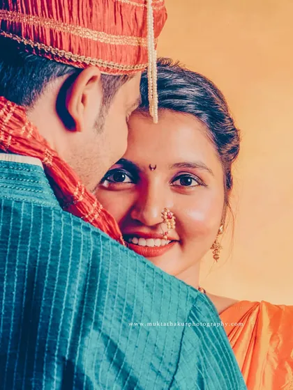 A stunning close-up of a Maharashtrian bride. Her joyful smile and traditional jewelry tell a story of heritage and happiness, captured in a warm, classic portrait.