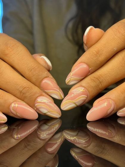 A full view of the graceful pink and gold swirl manicure.