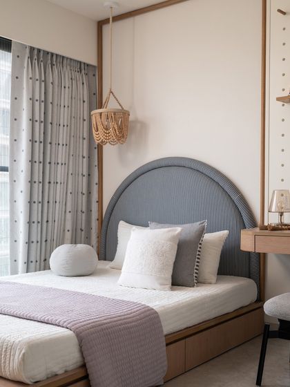A charming corner platform bed is beautifully framed in wood, showcasing a blue-and-white striped headboard and adorned with a lavender bedspread. The design is both cozy and stylish for a growing child.