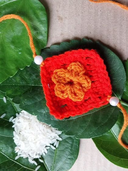 A granny square-inspired rakhi with a flower applique. This design has a lovely, vintage feel.