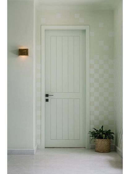 A detail of the family lounge, featuring a mint green door with vertical paneling and a checkered wall pattern. These quiet details add to the room's laid-back, joyful atmosphere.