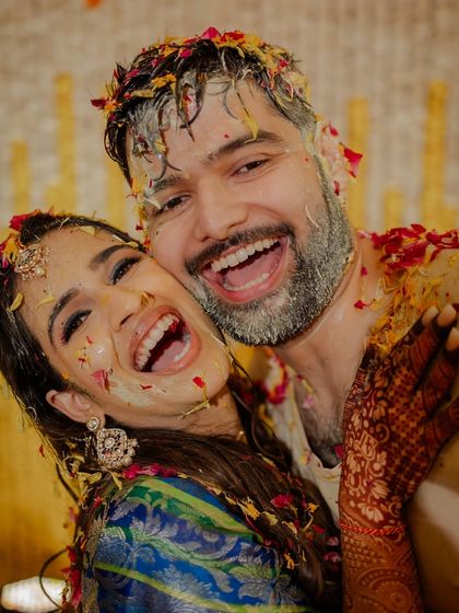 A tight embrace between the couple, both laughing and covered in yellow paste and flowers. This is what core memories are made of.