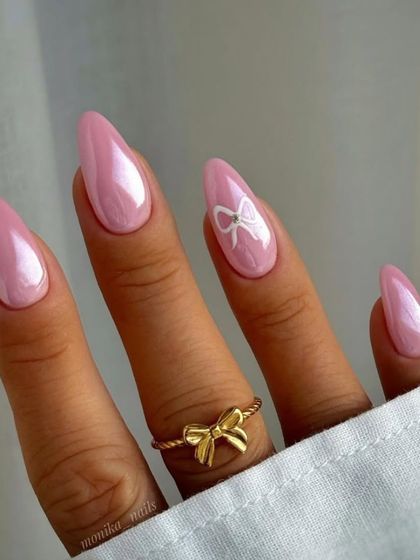 Nail inspiration for coquette nails, featuring a pearlescent pink base and a simple white bow accent.