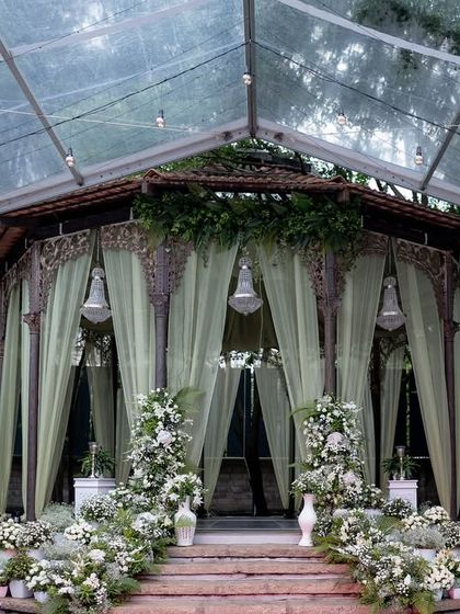 The Colonial Bandstand draped in soft green curtains and adorned with white flowers for an elegant Sangeet celebration.