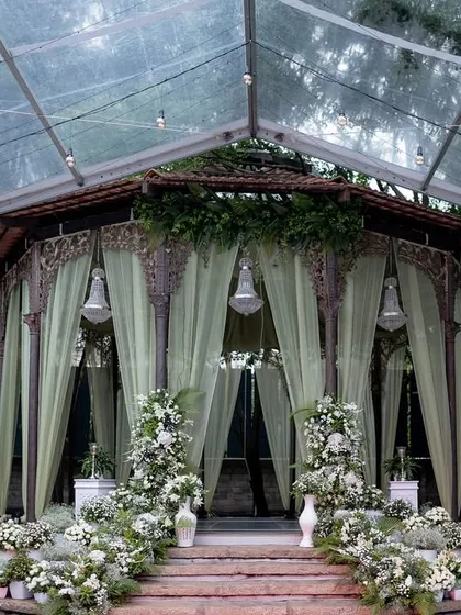 The Colonial Bandstand draped in soft green curtains and adorned with white flowers for an elegant Sangeet celebration.