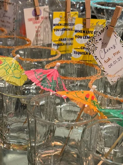 Fun and festive glasses ready for a party, garnished with colorful cocktail umbrellas and custom tags.