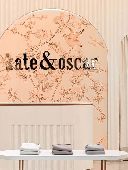 A centered shot of the main branding wall, flanked by clothing displays. The soft curtains behind the arches add a layer of softness and conceal back-of-house areas without disrupting the aesthetic.