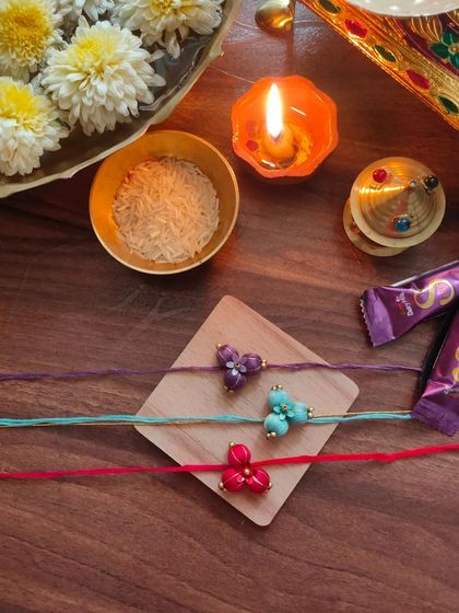 These beautiful floral rakhis are made from fabric beads and come in purple, teal, and red. Each one is carefully crafted by hand.