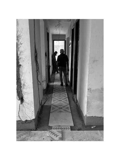 A patterned tile runner being installed in a hallway. Even in the midst of construction, the design begins to emerge.