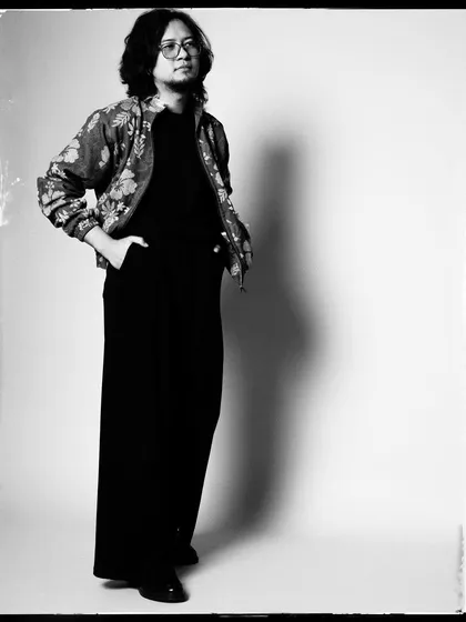 A classic, full-length black and white portrait of Taba Chake. The lighting is simple and clean, focusing on his silhouette.