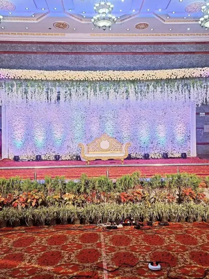 This reception stage is pure opulence, with a wall-to-wall backdrop of cascading white flowers. The sheer scale of the floral arrangement, combined with soft uplighting, creates an incredibly grand and luxurious setting for the couple.