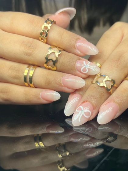 A different angle of the bow-accented French ombre nails, showing the subtle sparkle within the bow design.