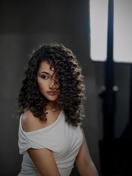 A dramatic, shadowy portrait of our curly-haired model from the campaign shoot.