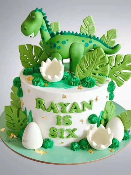 A lush green dinosaur-themed cake with edible leaves and dinosaur eggs. The fondant dinosaur topper and rich green details make this a standout piece for a jungle or dino party.