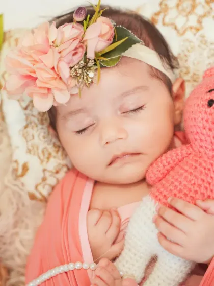 A close-up portrait of a newborn girl, complete with a floral headband and a cuddly teddy. These props are part of my collection and available for your session.