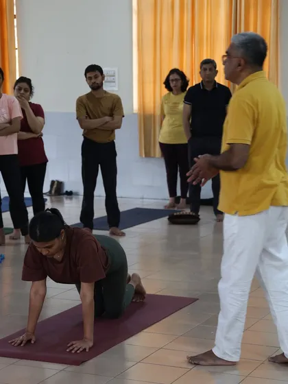 A teacher demonstrates the transition from the cat pose, a preparatory movement we teach to ensure students move safely into the Surya Namaskar sequence.