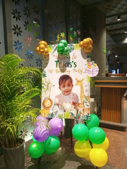 A jungle-themed welcome sign on an easel with balloon accents at the entrance of a party.
