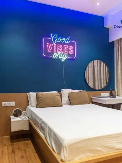 We help you create a space that reflects your personality. This bedroom features a bold blue accent wall and a fun "Good Vibes Only" neon sign, making it a vibrant and personal retreat.
