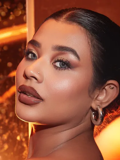 A classic soft glam look with a brown smokey eye and a glossy nude lip, beautifully lit to create a warm, inviting feel.