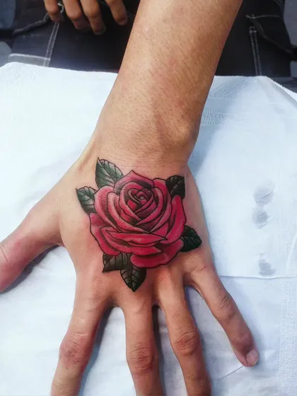 A classic, vibrant red rose tattooed on the hand. This timeless symbol of love and beauty is executed with bold color and clean lines.