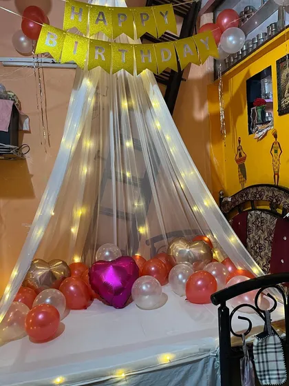 Another angle of the romantic canopy bed decoration. The warm lighting and scattered balloons create a perfect ambiance for a special birthday surprise.